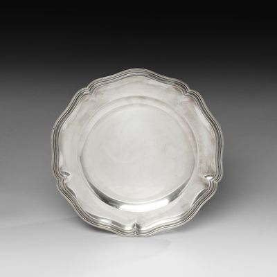 une assiette en argent aux bords festonnés sur un fond blanc