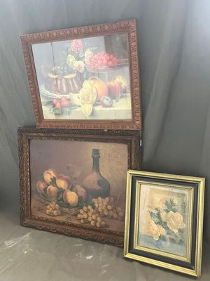 deux tableaux encadrés représentant des fruits et des fleurs posés sur une table, à côté d'un vase