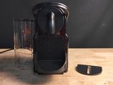 une cafetière noire posée sur une table à côté d'un verre d'eau