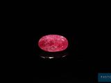 un rubis rose de forme ovale sur un fond noir