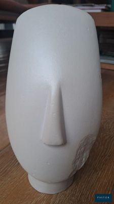 un vase blanc orné d'un visage, posé sur une table