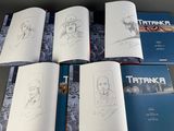 six books of comics are lined up on a table