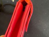 a person holding a red purse on a table