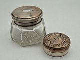 a small glass jar with a silver lid next to a small glass jar with a silver lid