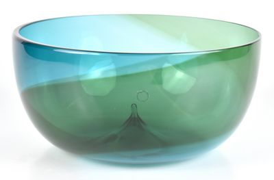 un bol en verre bleu et vert posé sur une surface blanche