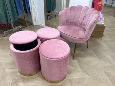 une chaise rose et trois tabourets devant un miroir