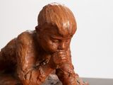 a small statue of a boy sitting on a rock