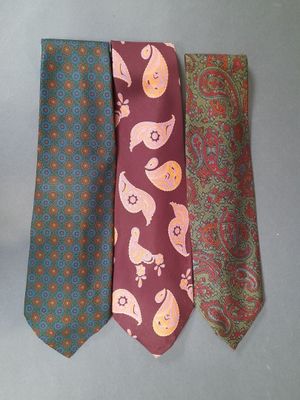 three ties with different designs on them on a gray surface