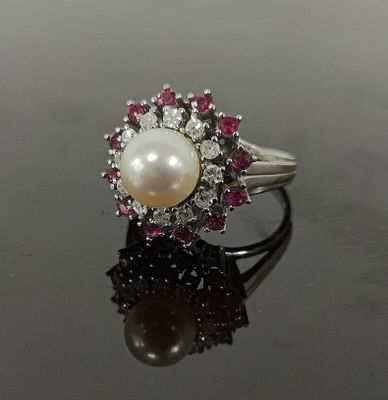 une photo d'une bague en perle et diamant posée sur un fond noir