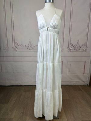 the white dress is on a mannequin stand in front of a wall
