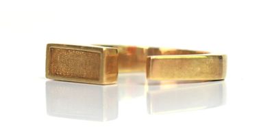 paire de bracelets manchette plaqués or sur fond blanc avec reflets