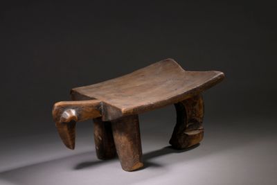 une image représentant un banc en bois aux pieds sculptés, sur fond gris