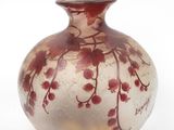 un vase en verre orné de fleurs rouges, posé sur une surface blanche