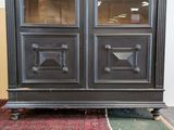 a black cabinet with glass doors and a rug on the floor