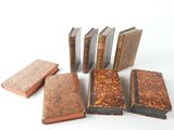 several old books are lined up in a row on a white surface