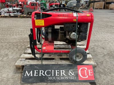 un petit générateur rouge posé sur une palette dans un entrepôt