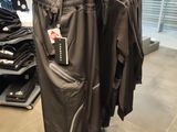 a rack of clothing in a store with a man standing in the background