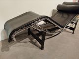 black leather chaise lounger and ottoman in a corner of a room