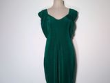 une robe verte posée sur un mannequin contre un mur blanc