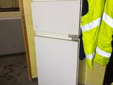 a white refrigerator sitting in a room with a yellow jacket on it