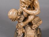 statue d'un homme tenant un livre et une balle, assis sur un livre