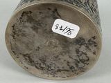 an old silver cup with a sticker on it sitting on a table