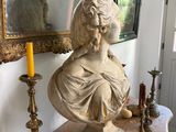 a statue of a woman sitting on a table in front of a mirror