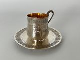 une tasse et une soucoupe en argent posées sur une assiette à soucoupe