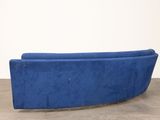 a blue couch sitting on top of a cement floor next to a white wall