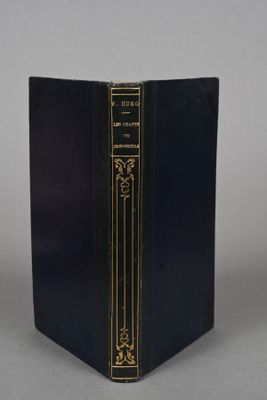 an old black book with gold trim sitting on top of a table