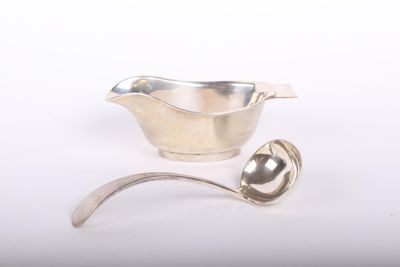 une cuillère en argent et un bol en argent posés sur une surface blanche