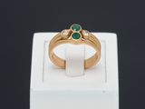 a close up of a gold ring with two emerald stones