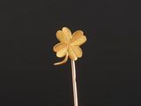 a gold four leaf clover on a stick against a black background