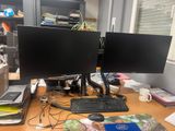 two computer monitors sitting on top of a wooden desk