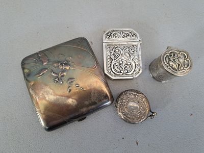 Plusieurs objets en argent sont posés sur une table recouverte d'une nappe blanche.