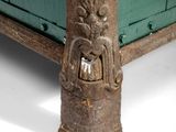 a close up of a green bed with a carved headboard