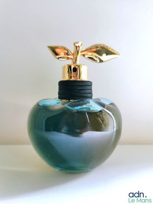 une bouteille en verre bleu surmontée d'une feuille d'or