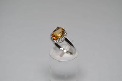 an oval citrine and diamond ring on a clear glass