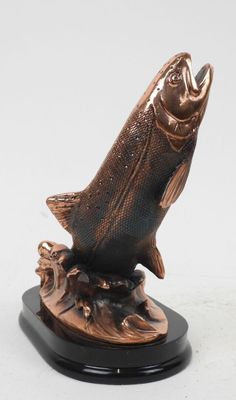bronze fish sculpture on black base on white background