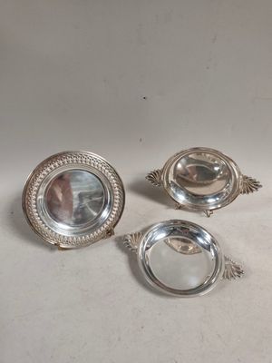 trois plats en métal argenté posés sur une table, avec un miroir au milieu