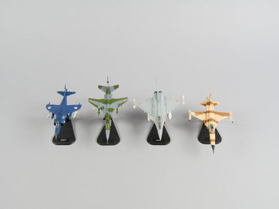 trois petits modèles réduits d'avions sont alignés sur une surface blanche