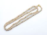 un collier de perles à un rang avec un fermoir en or sur fond blanc