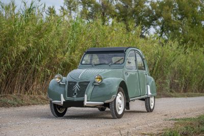 a small green car that is driving down a dirt road
