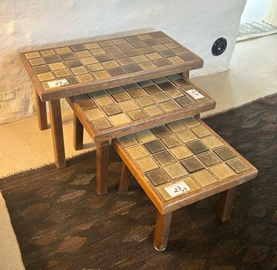 two tables with tile on them sitting on a rug