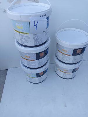 several buckets of paint sitting on a white surface next to a wall