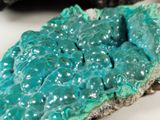 close up of a piece of green and blue mineral on a white surface