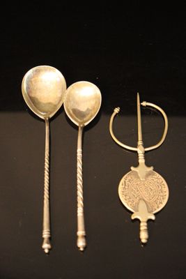 trois cuillères en argent et deux cuillères en argent sur un fond noir