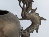 a metal vase with a dragon on it and a fish on it