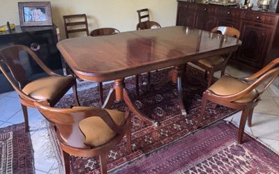 a dining room table with chairs and a rug on the floor