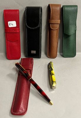 quatre stylos et un étui sont alignés sur une surface blanche